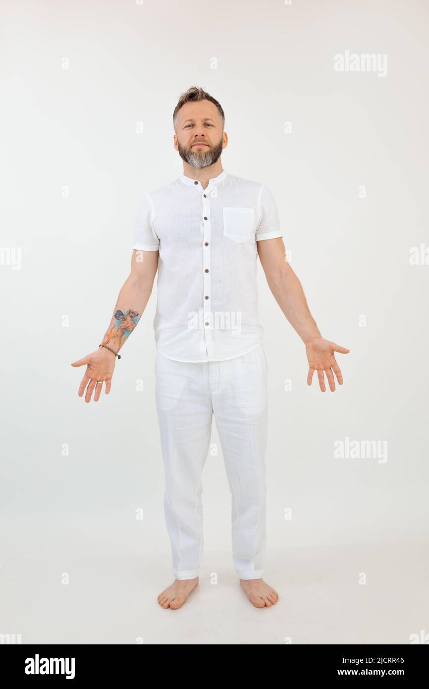 Vertical studio shot handsome barefoot man in white outfit. Yoga sports instructor Asana and trust exercise. Copy space Stock Photo