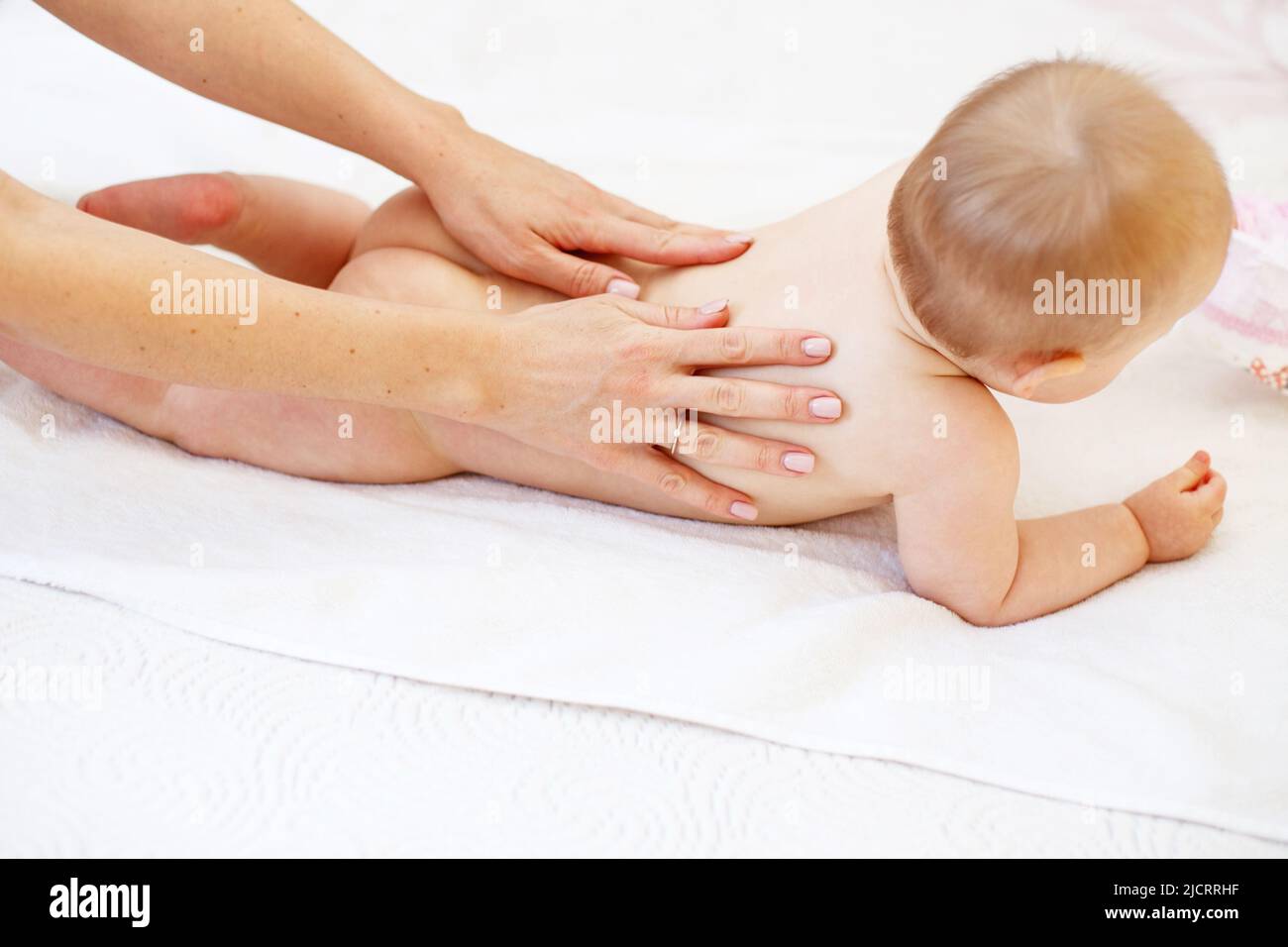 Mother massaging baby in the bed at home Stock Photo