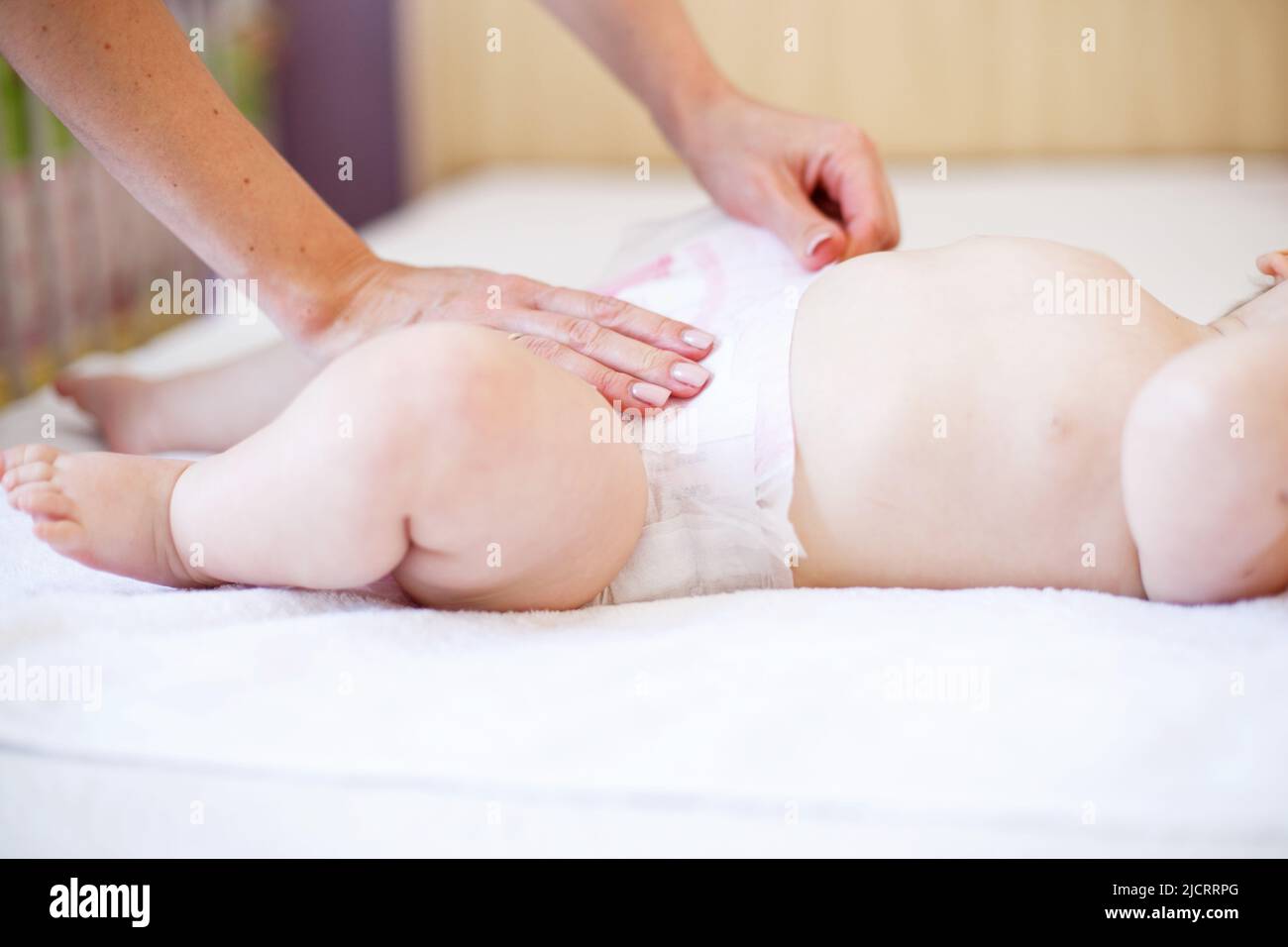 Caring young mother changing the diaper of her baby at home Stock Photo
