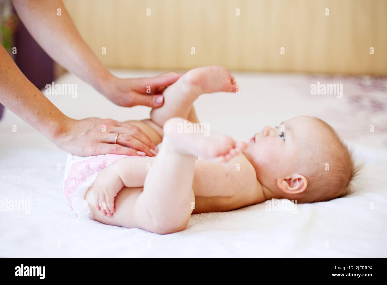 Caring young mother changing the diaper of her baby at home Stock Photo