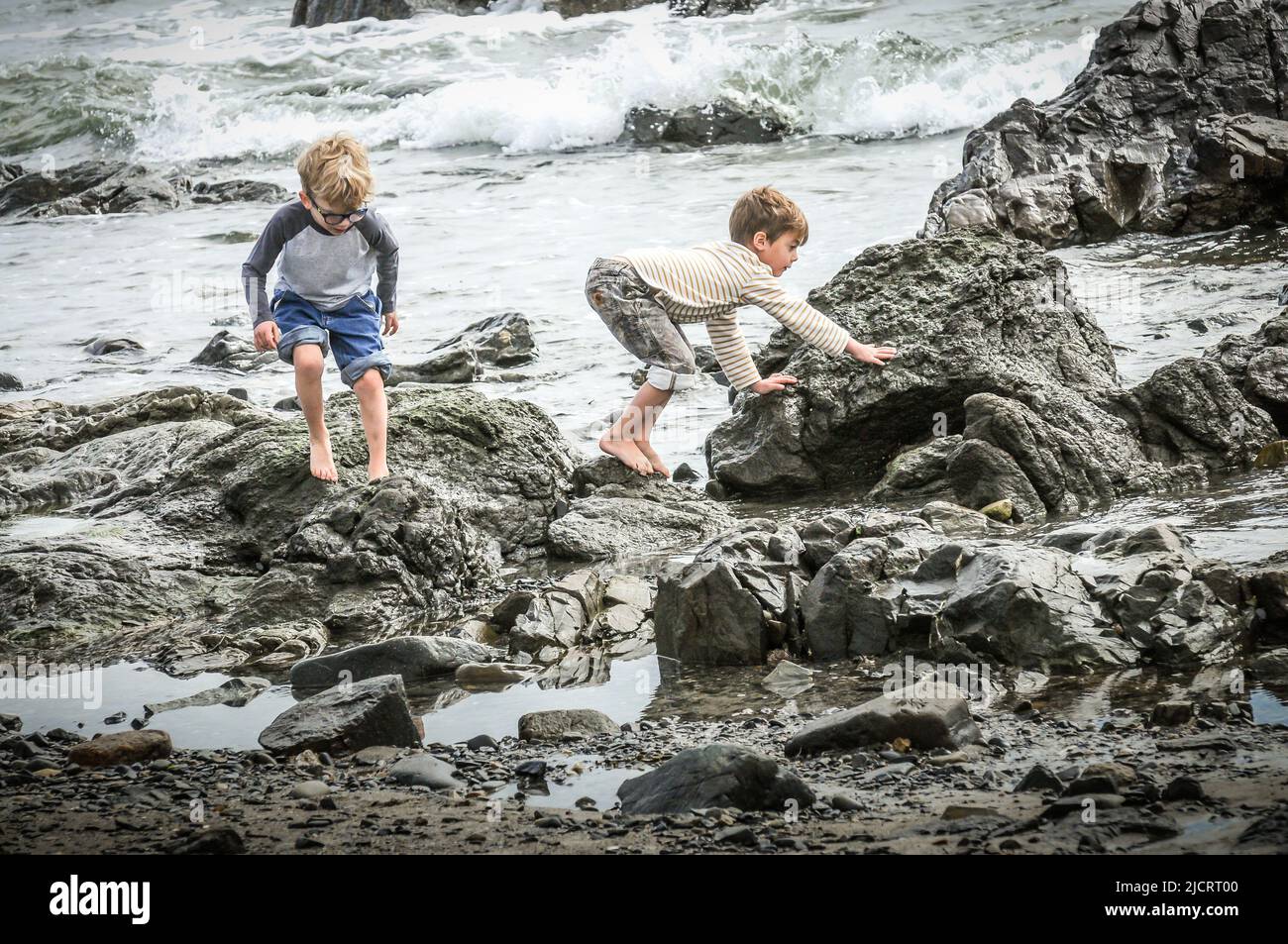 Little boys find rocks to go climbing on, add water, and it is a day of pure fun. Their feet may be a little sore at the days end, but what fun. Stock Photo