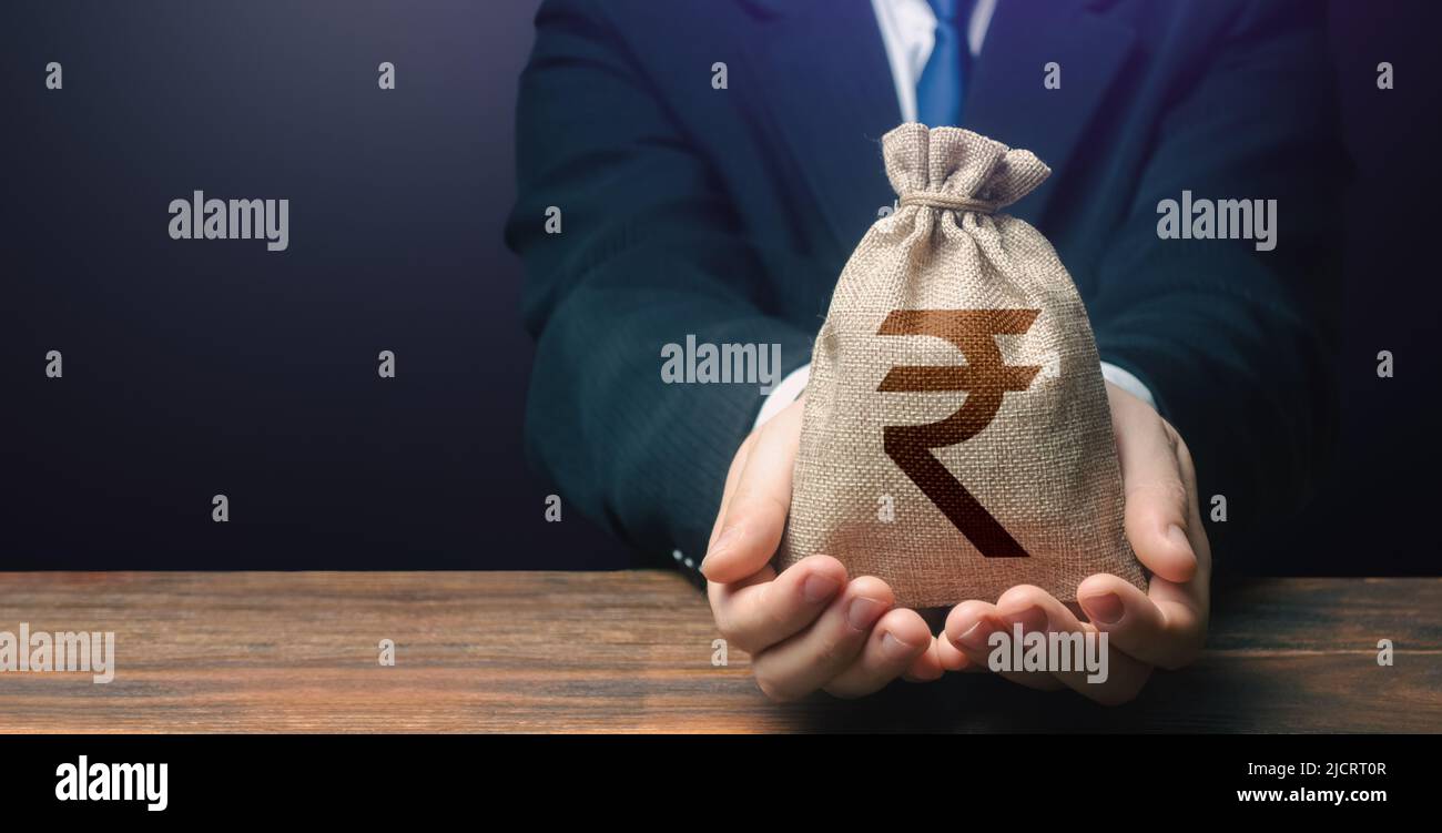 Businessman holds out indian rupee money bag. Getting a grant 