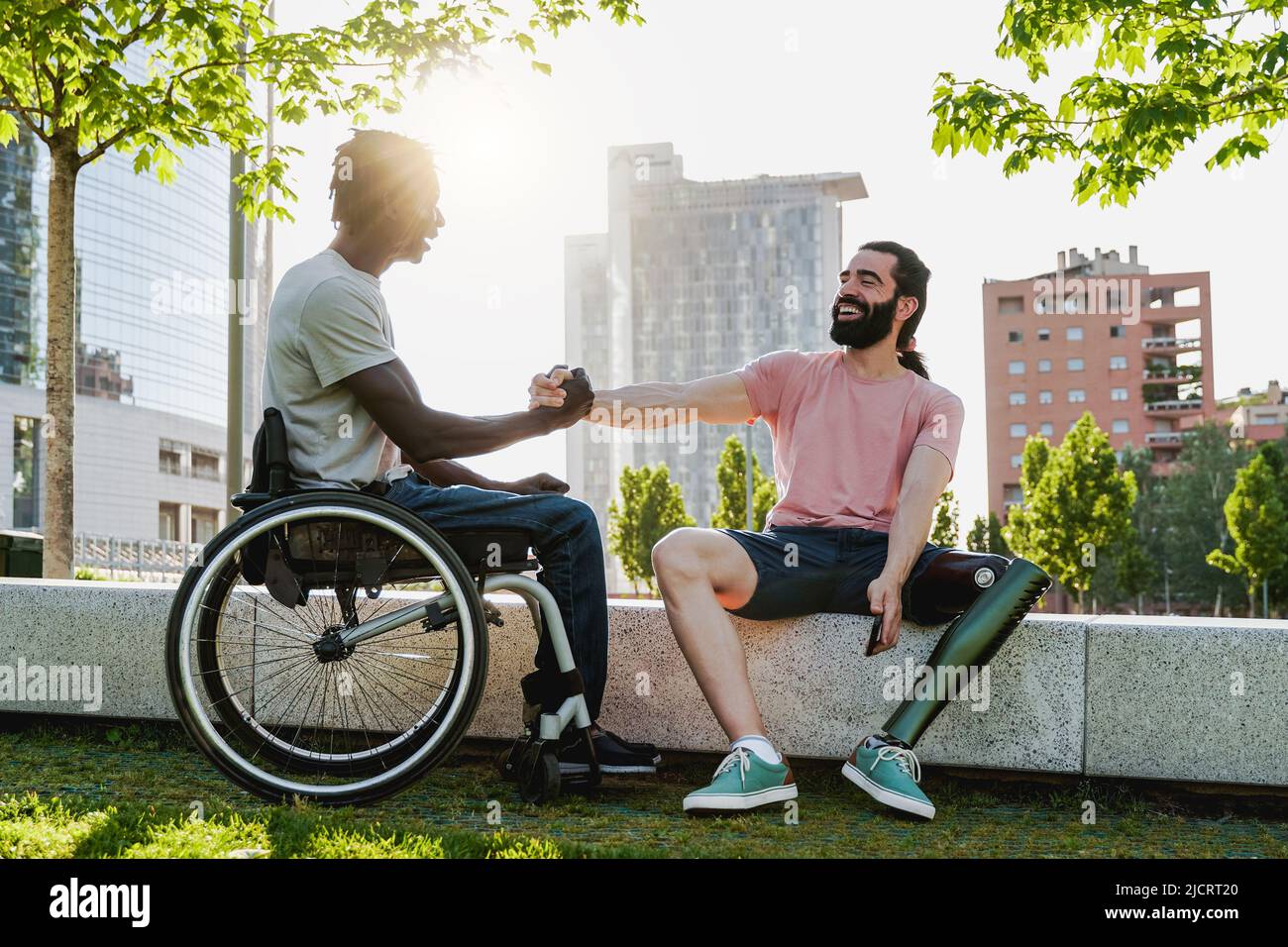 Multiethnic people with disabilities greeting each other outdoor - Focus on right man with leg prosthesis Stock Photo
