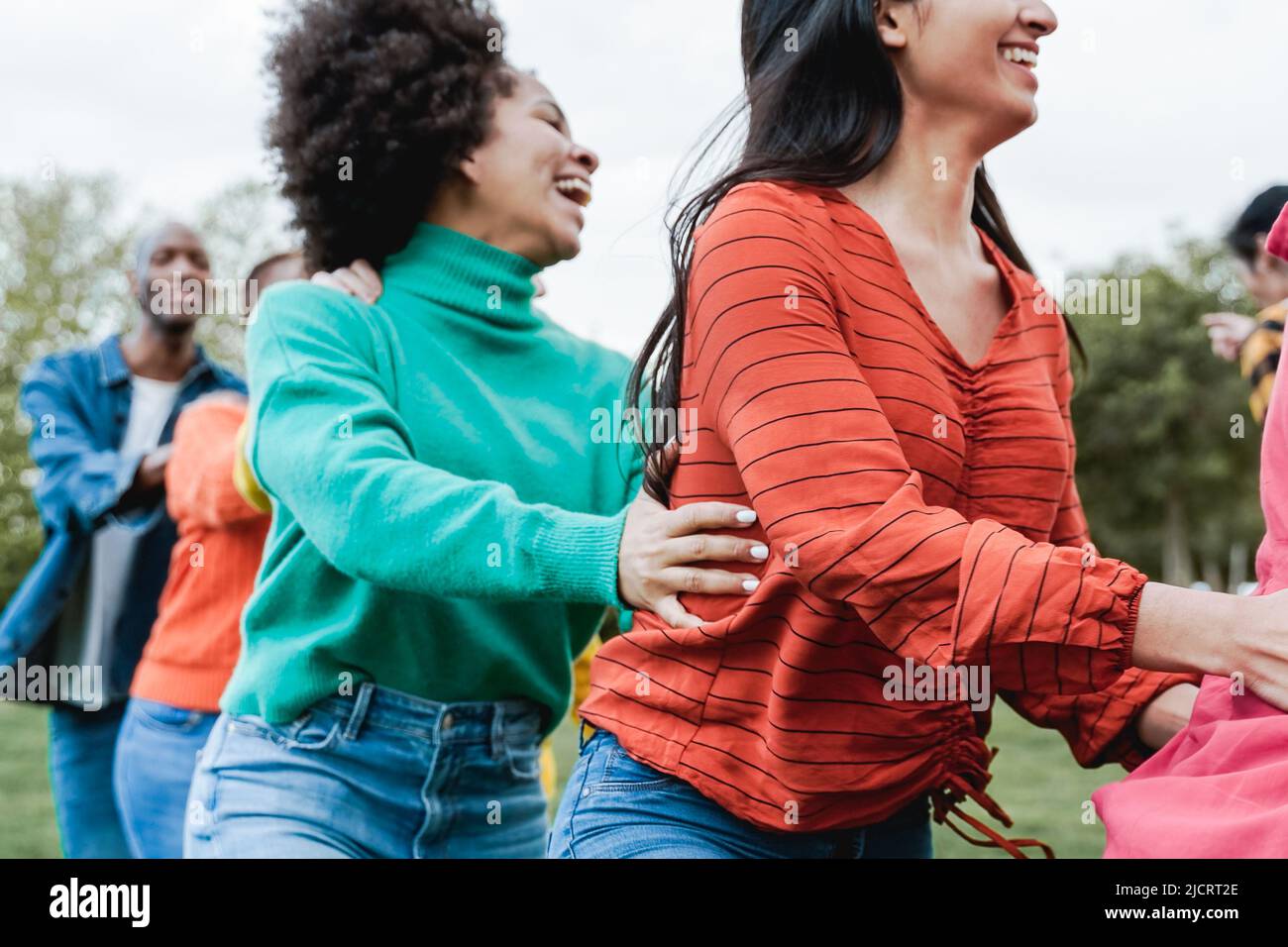 Multiethnic people dancing outdoor - Happy friends having fun at park city - Focus on right girl arm Stock Photo