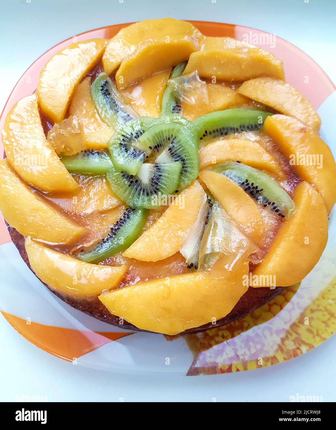Glazed fruit flan or pie with sliced kiwi fruit and peach, top view