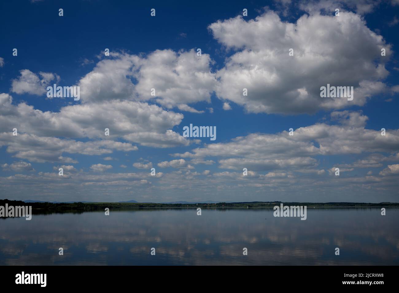 Blue sky with white clouds reflecting on the water Stock Photo - Alamy