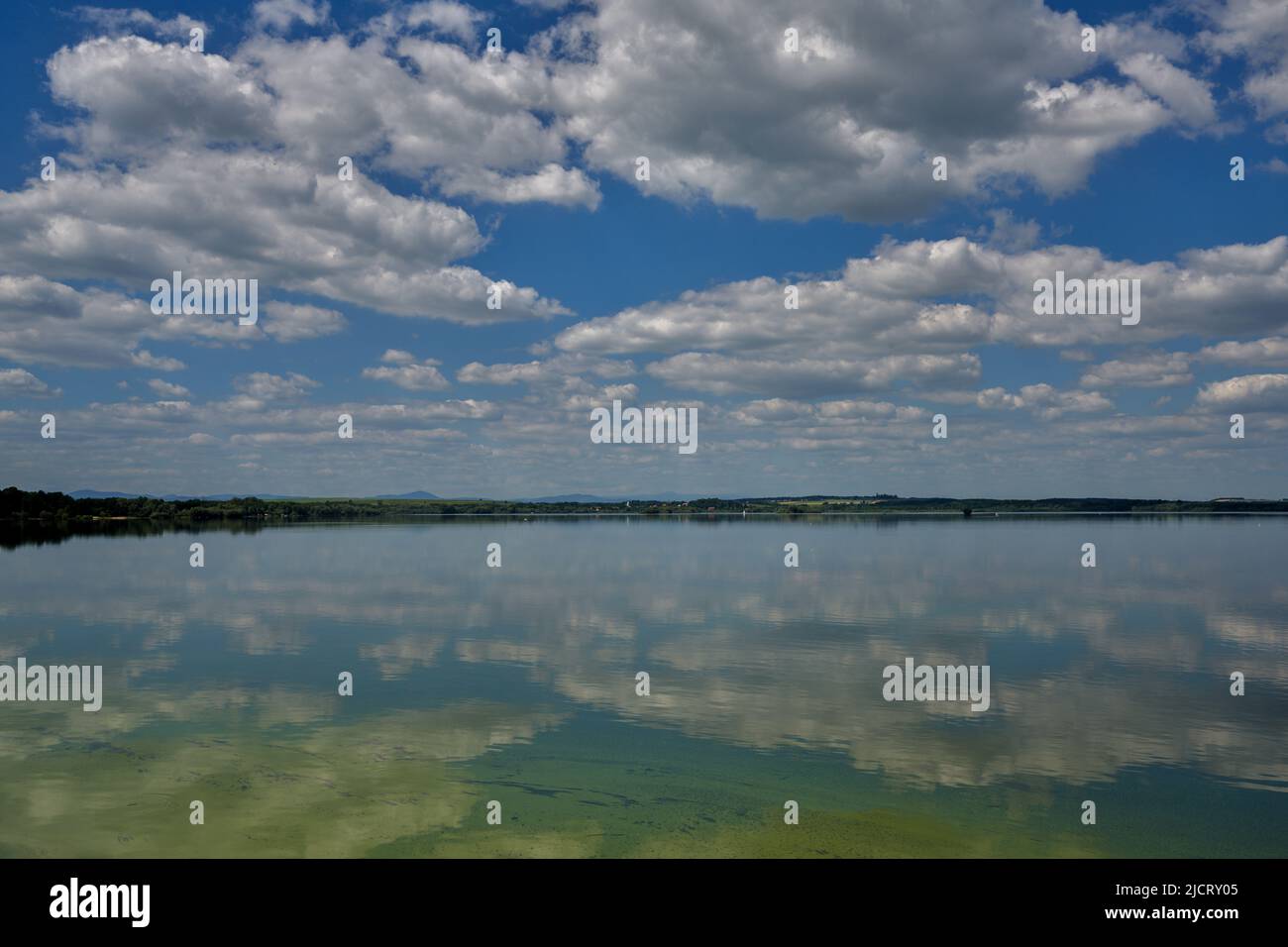 Blue sky with white clouds reflecting on the water Stock Photo - Alamy