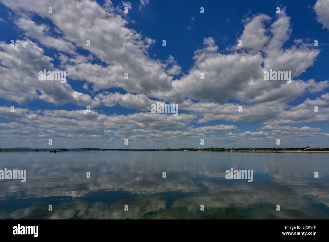 Blue sky with white clouds reflecting on the water Stock Photo - Alamy