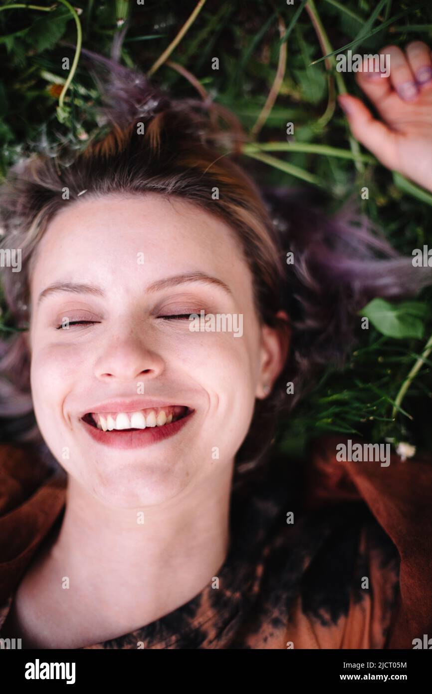 Portrait of happy young woman lying on grass in spring Stock Photo - Alamy