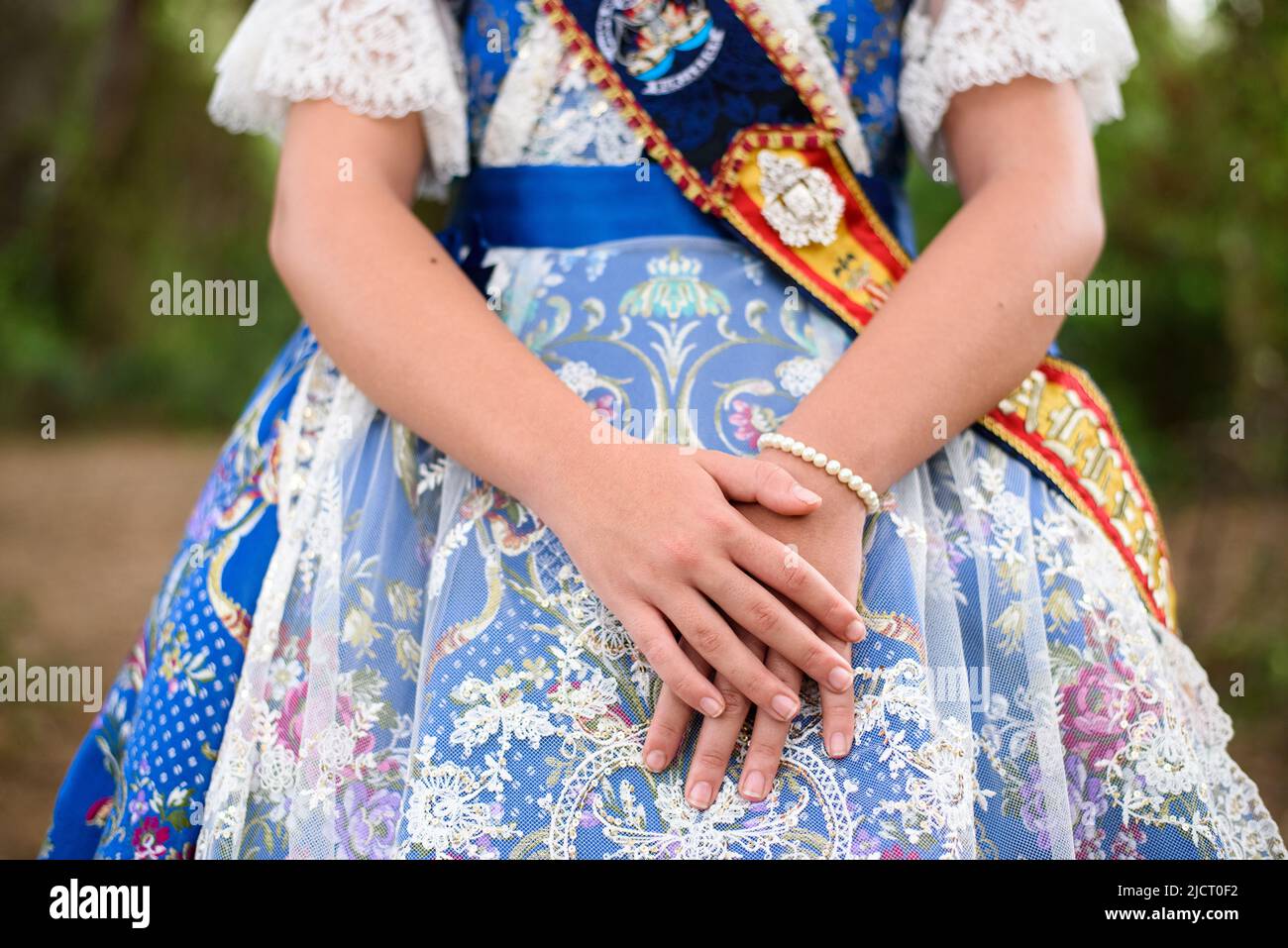 Detail of a traditional Valencian fallera dress, with beautiful embroidery, crossed hands. Stock Photo