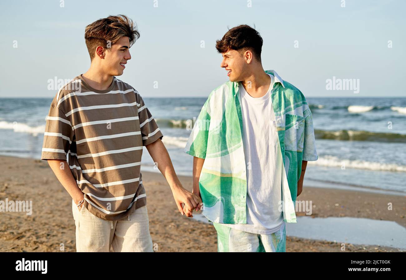 Happy Gay Couple Walking Along The Beach Together Stock Photo