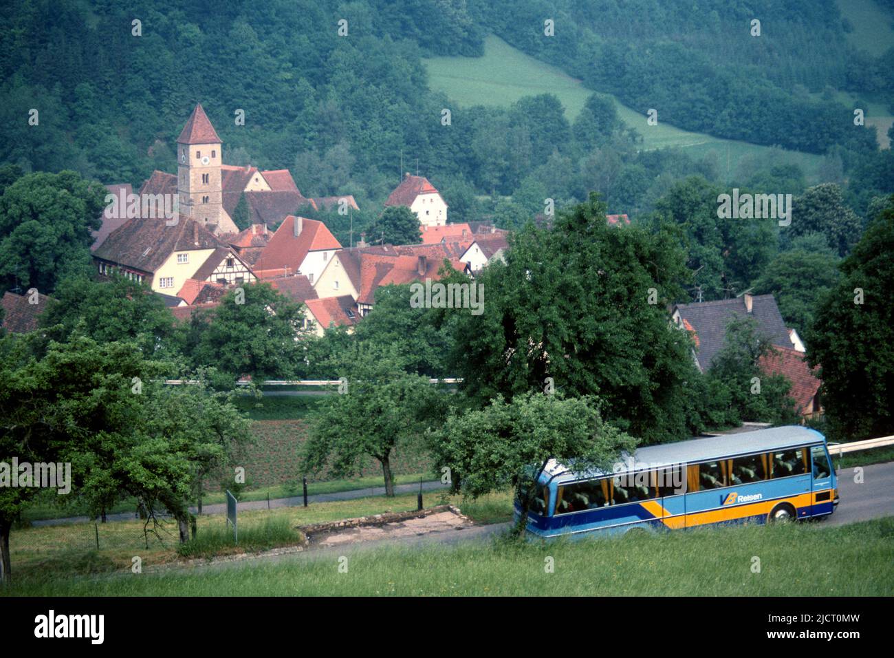 View of village from hillside with tourist coach on the road in 1982, Detwang, Rothenburg ob der Tauber, Bavaria, Germany Stock Photo