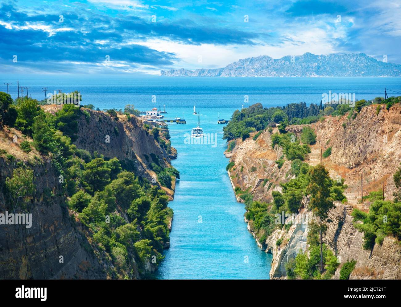 Beautiful landscape of the Corinth Canal in a bright sunny day against a blue sky with dramatic clouds. A pleasure boat floats among the rocks.Greece Stock Photo