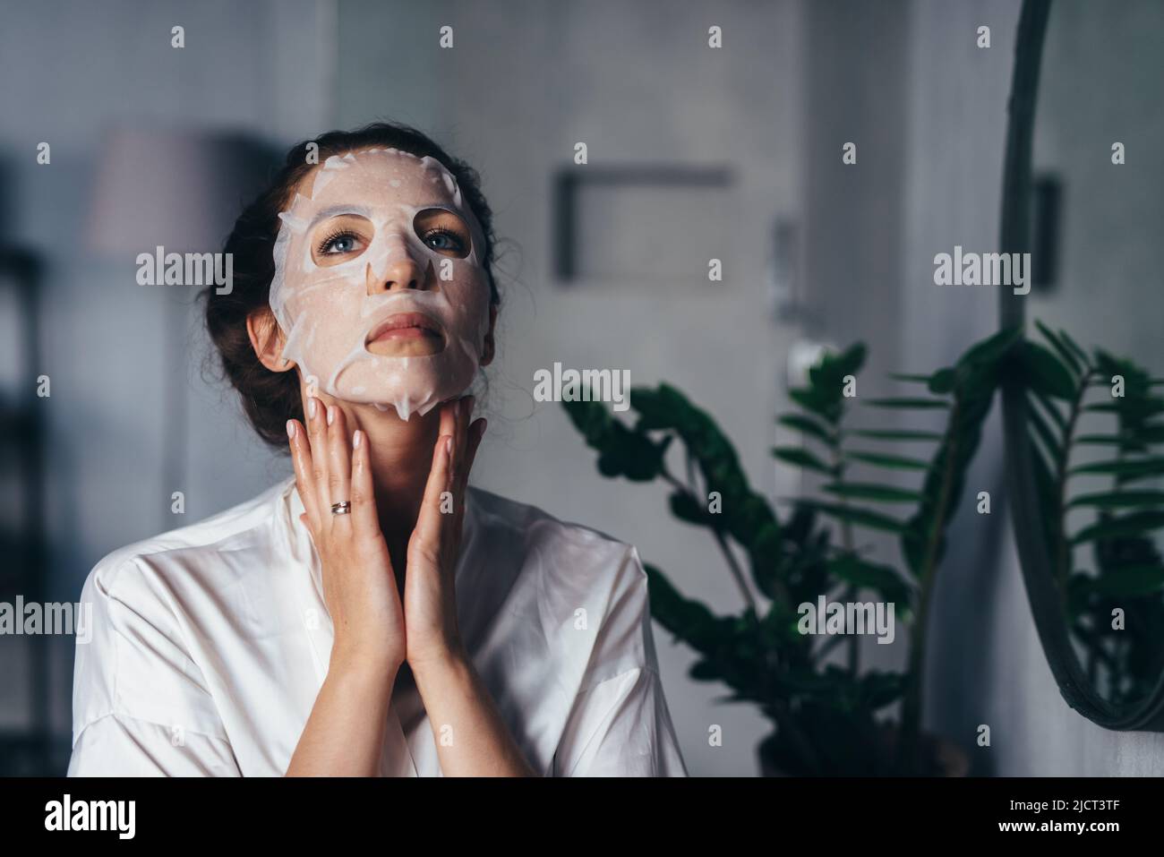 Home care for the skin of the face and neck. A young woman makes a rejuvenating, nourishing treatment at home. Stock Photo