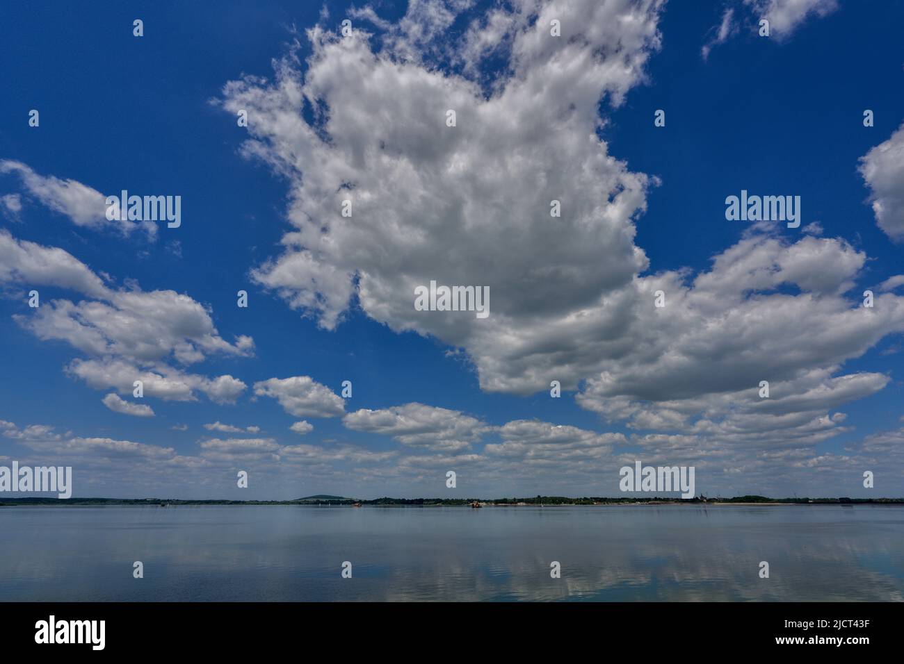 Blue sky with white clouds reflecting on the water Stock Photo - Alamy