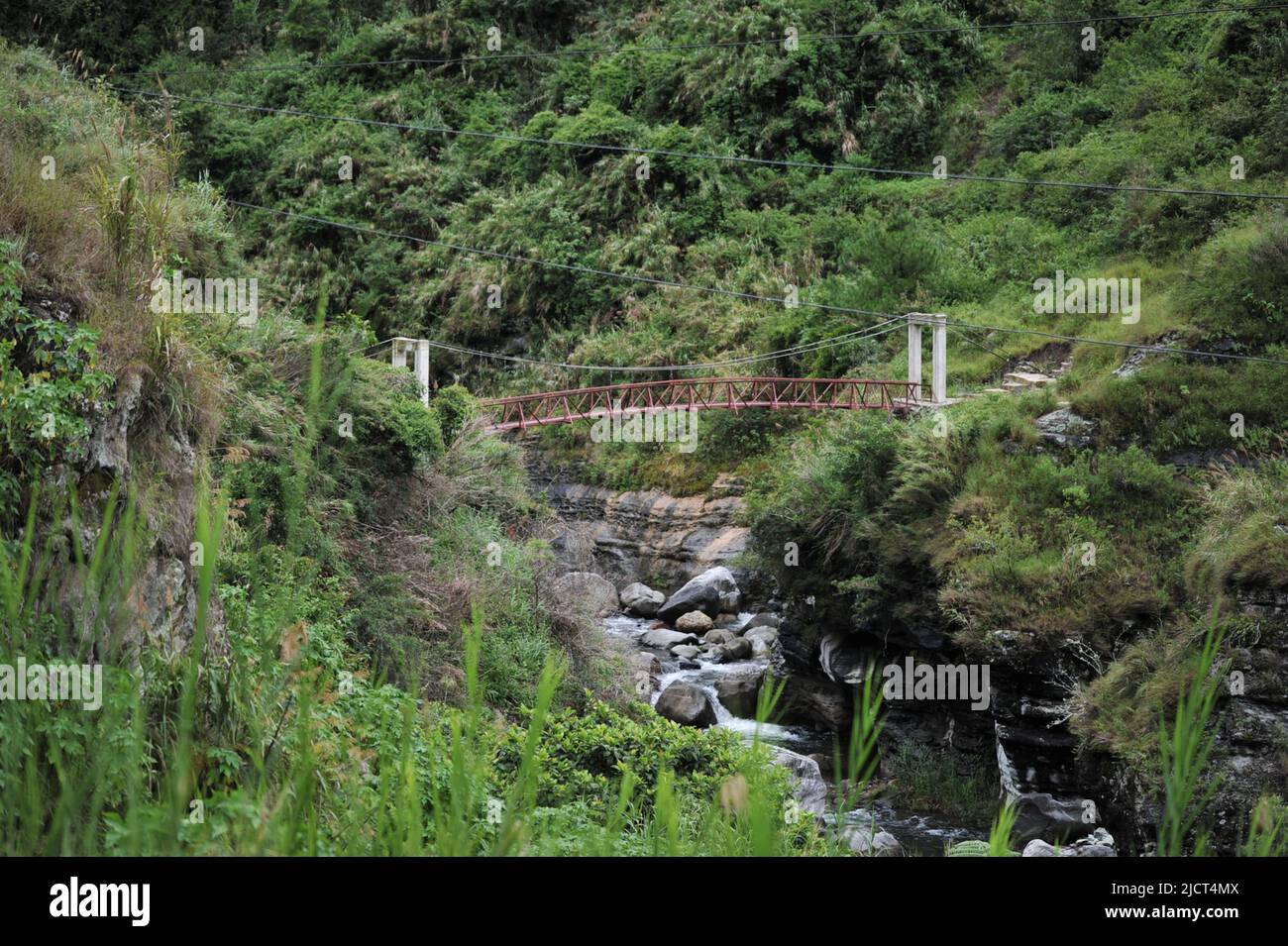 Mountain Province, Philippines: narrow metal bridge on top of a rocky stream on the way to Bomod-ok Falls. Stock Photo