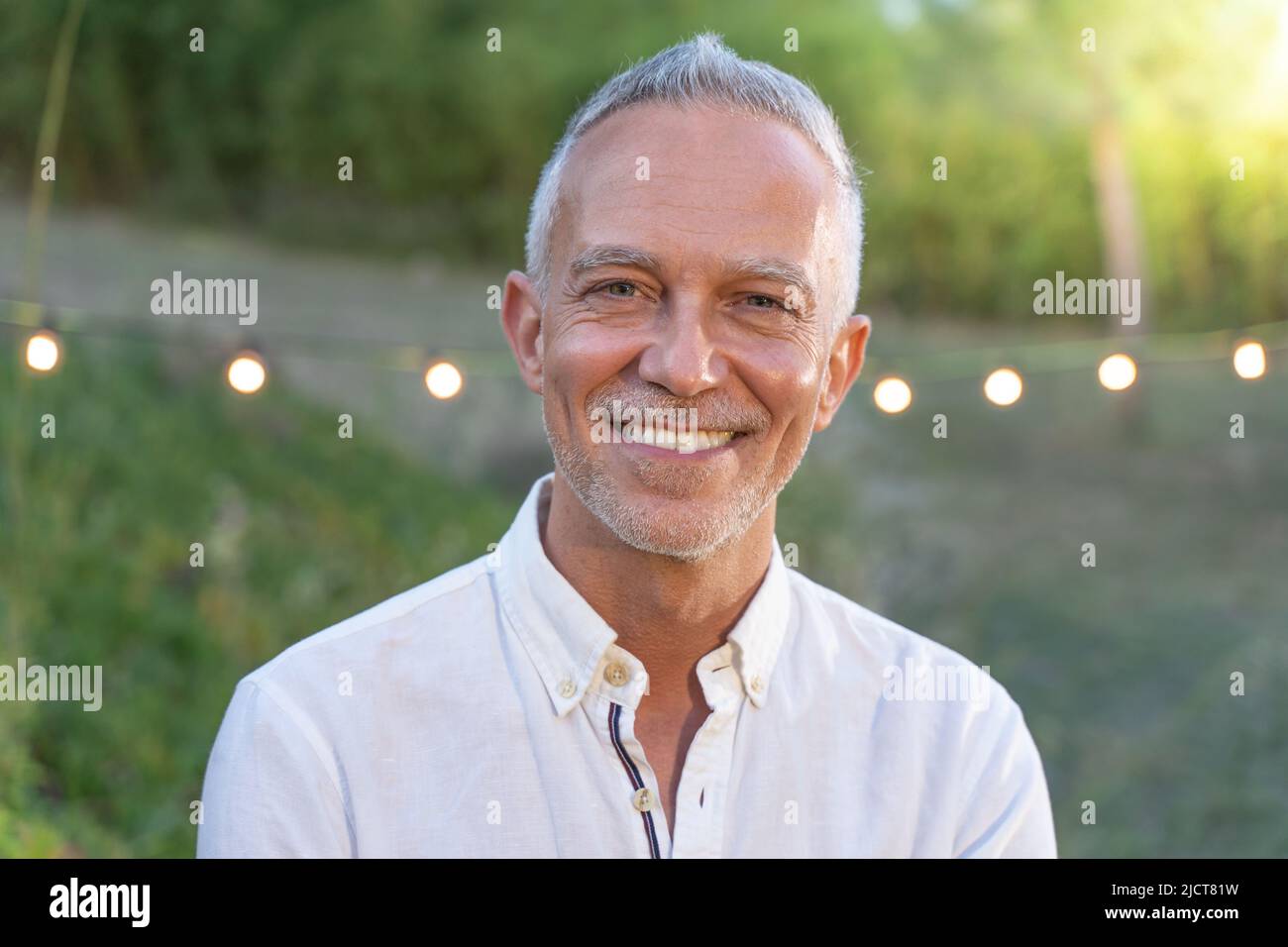 Middle-aged good looking man posing smiling in nature background. Stock Photo
