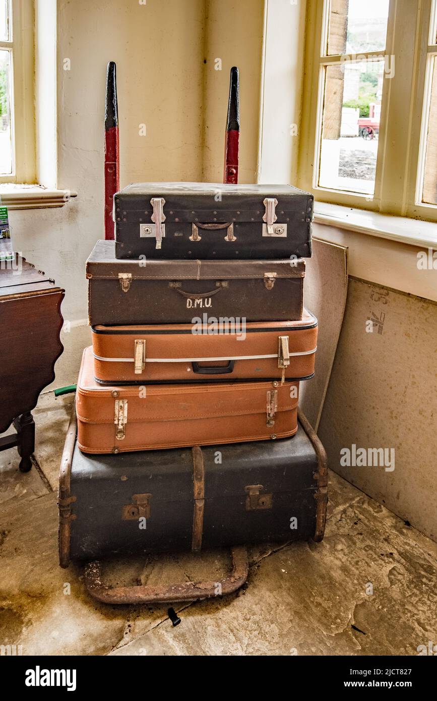 Stack of old suitcases on an old luggage trolley, on display in the waiting room at Settle railway station, in North Yorkshire,England, UK. Stock Photo