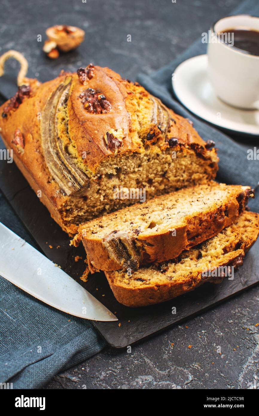 Banana bread or cake with chocolate and walnuts with cup of coffee. Delicious homemade dessert, tasty snack or morning breakfast Stock Photo