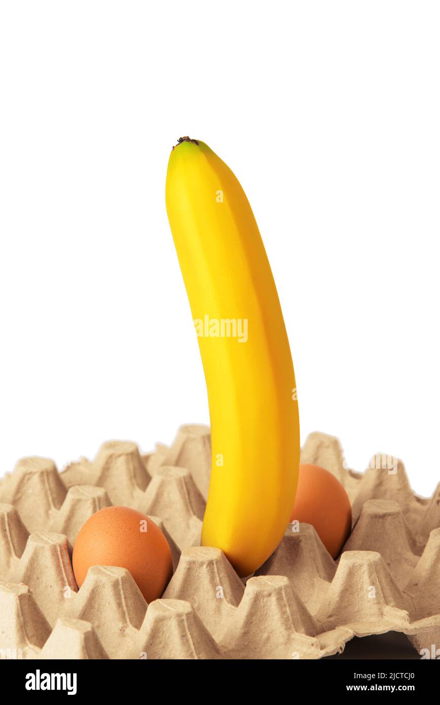 Big ripe banana and two chicken eggs in egg carton on white background. Sexy concept Stock Photo