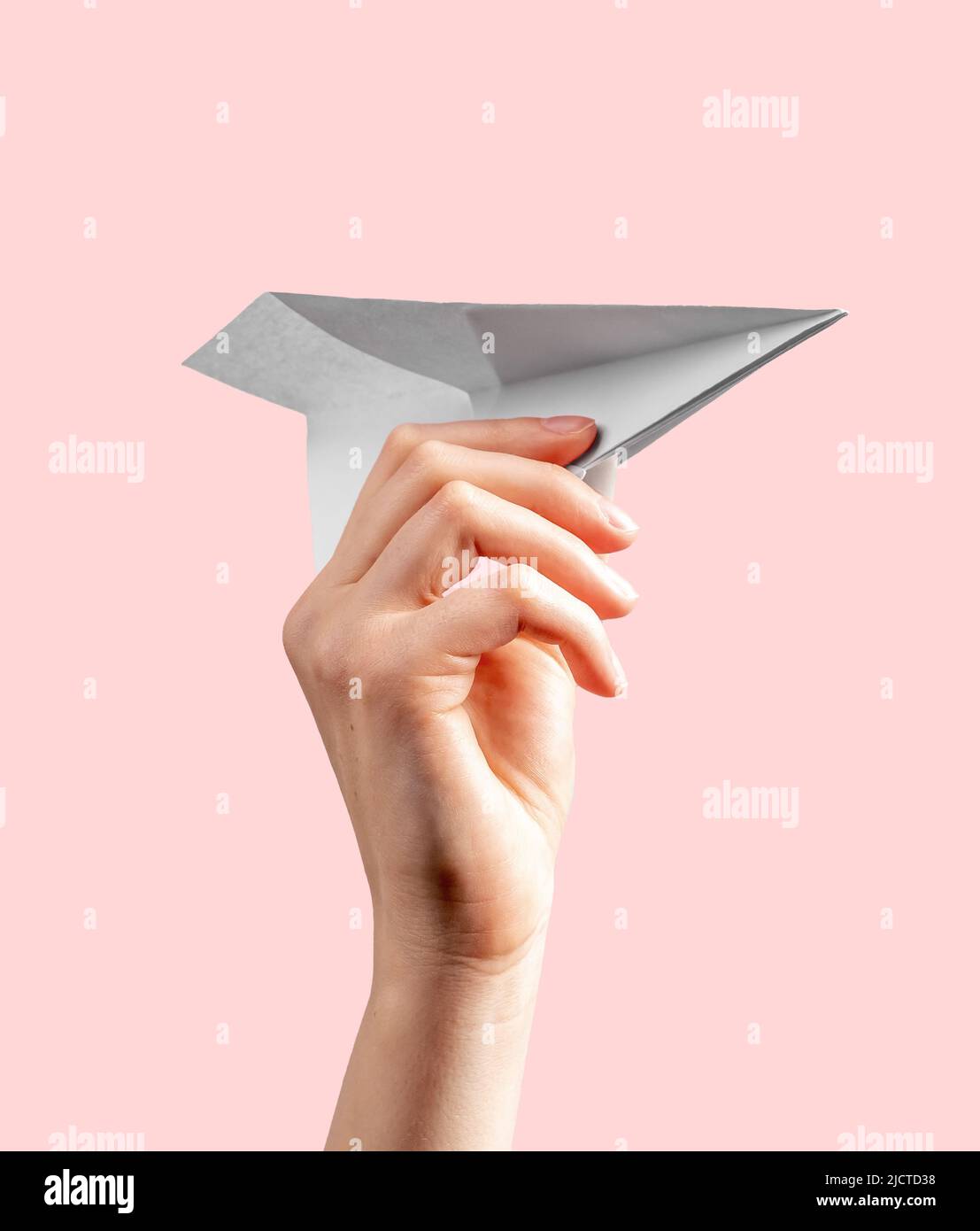 Woman hand throwing origami plane on pink background. Symbol of childhood, freedom, imagination, creativity. Paper folding art. High quality photo Stock Photo