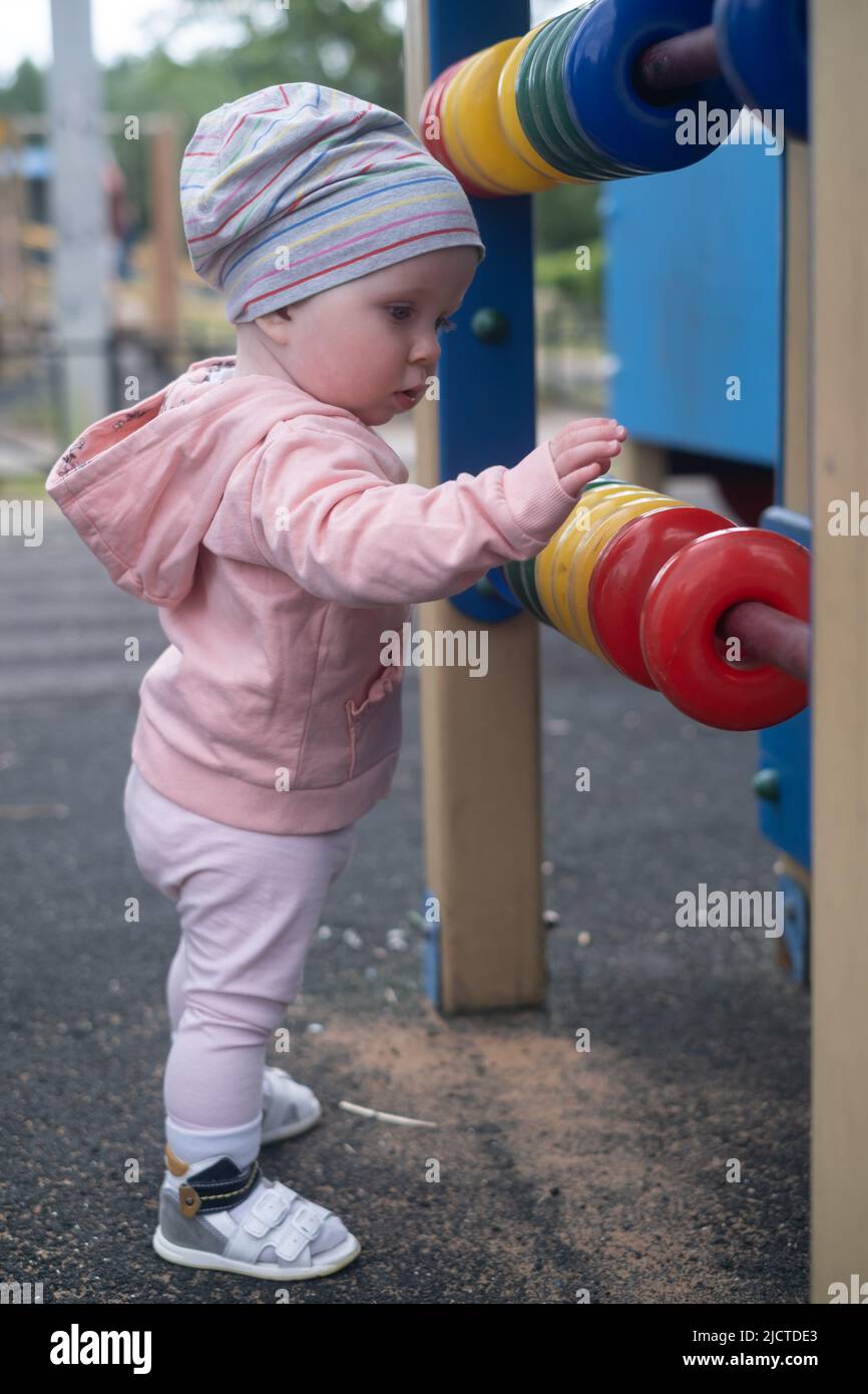 Caucasian baby girl playing with colored rings on playground. Stock Photo