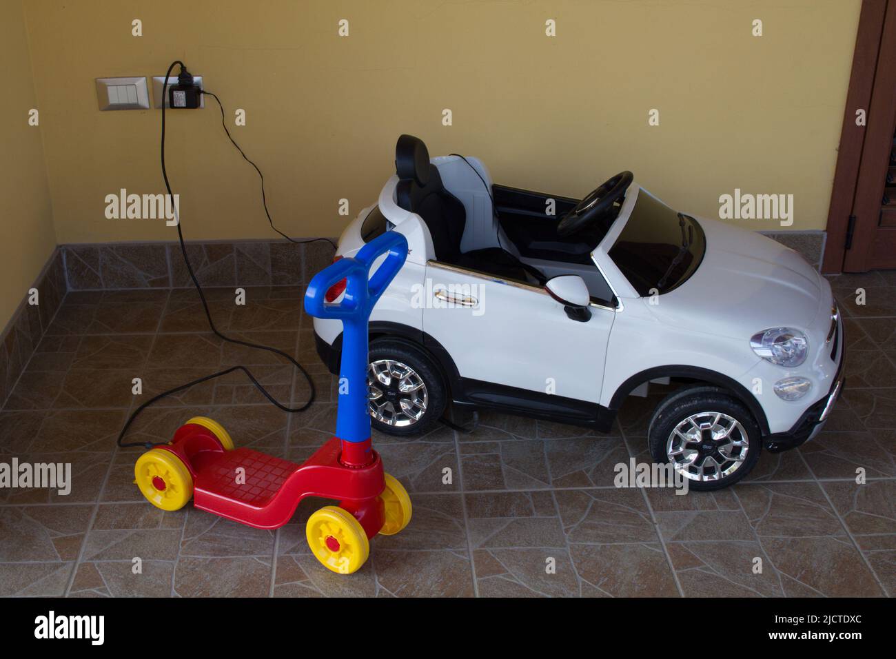 Nice picture of an electric car and a toy scooter while they are charging electrically. Stock Photo