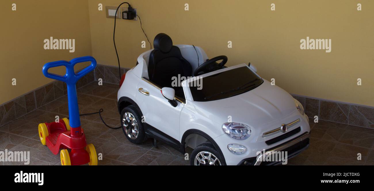 Nice picture of an electric car and a toy scooter while they are charging electrically. Stock Photo