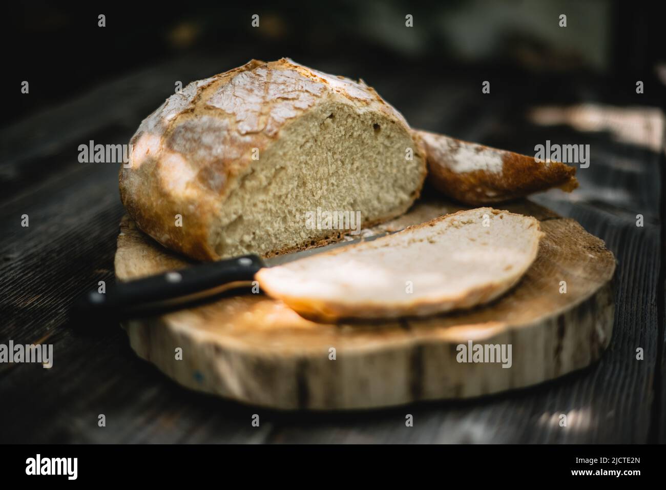 Traditional leavened sourdough bread cut into slice on a rustic wooden table. Healthy food photography Stock Photo