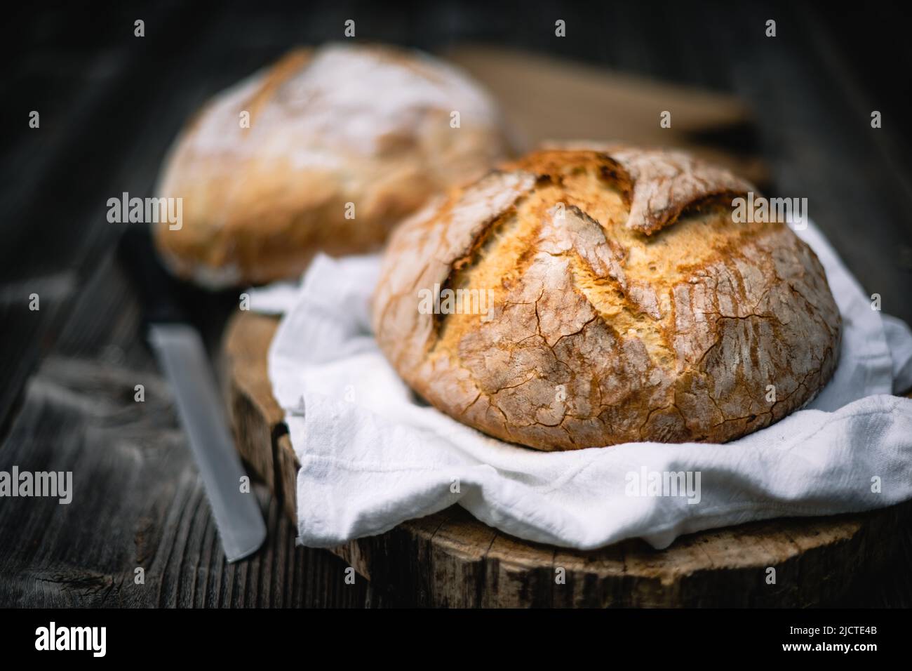 Traditional leavened sourdough bread with rought skin on a rustic wooden table. Healthy food photography Stock Photo