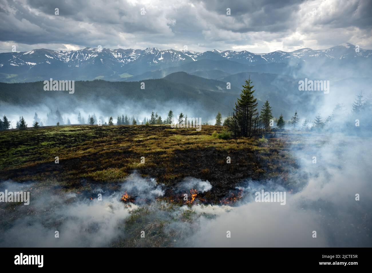 Naturally burning mountains in Ukrainian Carpathians. Mountains in fire. Dry grass burn in spring time Stock Photo