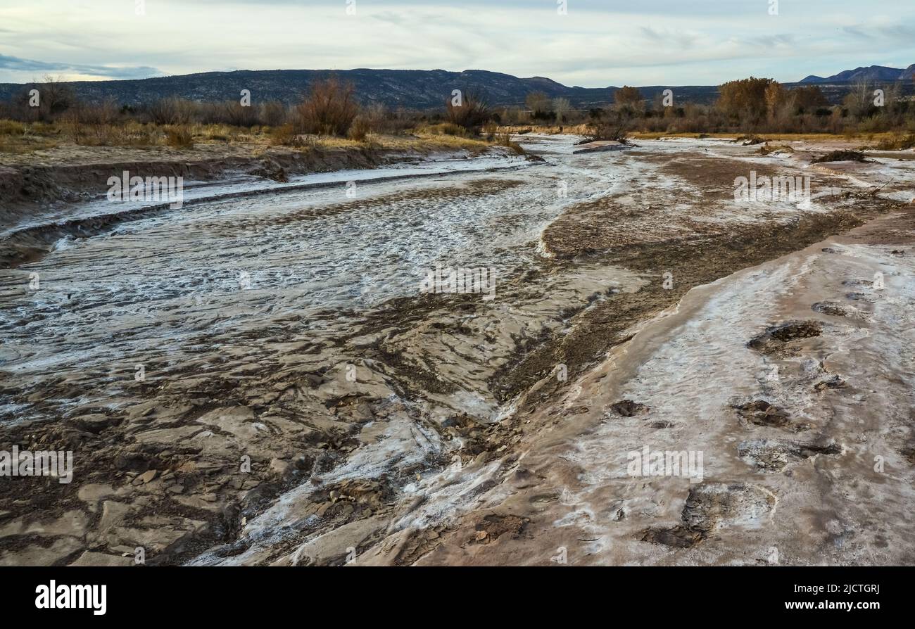 Cracked red clay and white salt on the surface in a dried riverbed in