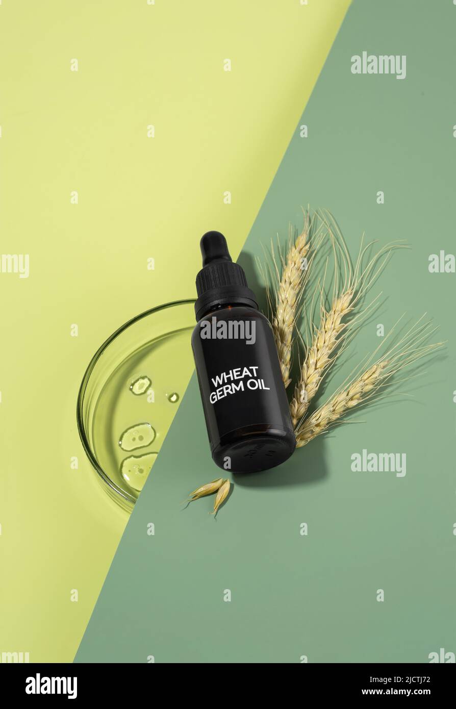 Glass bottle of wheat sprouts oil with dropper laying on a green