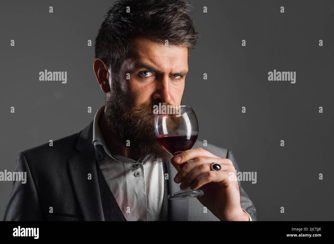 Winemaker smelling red wine in glass. Bearded sommelier tasting flavor and checking wine quality. Stock Photo