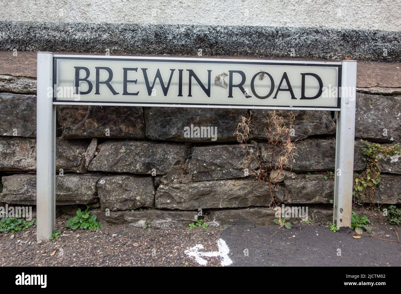 Brewin Road street name sign on two posts with an old stone wall in the ...