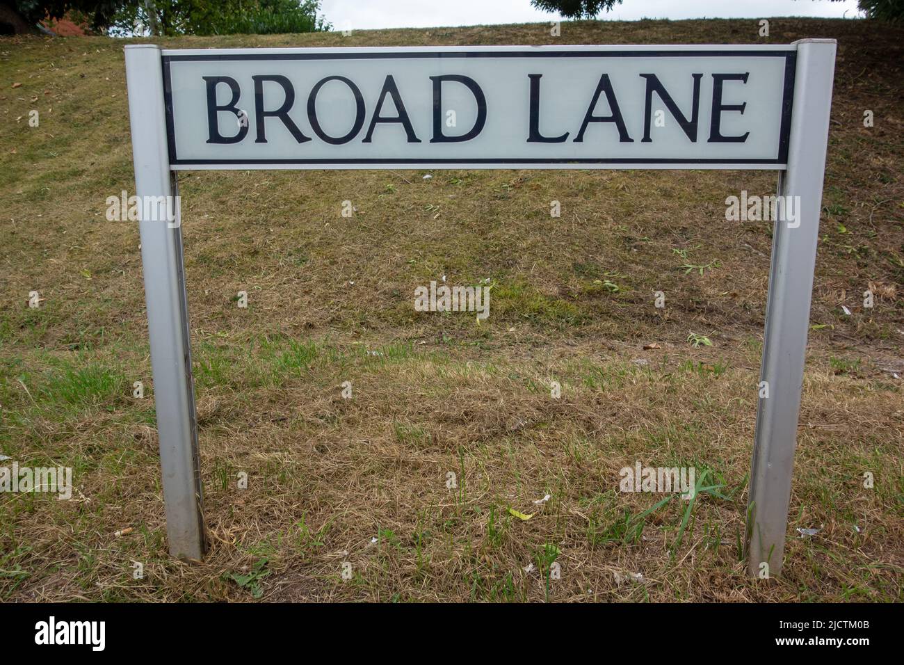 Broad lane street name sign on two posts with grass in the background Stock Photo