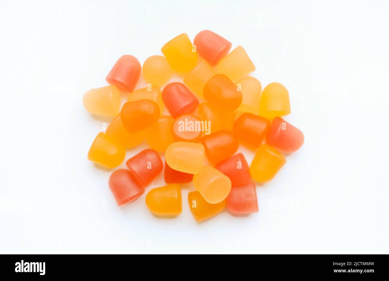 Close-up texture of orange and yellow multivitamin gummies in the form of bears on white background.  Stock Photo