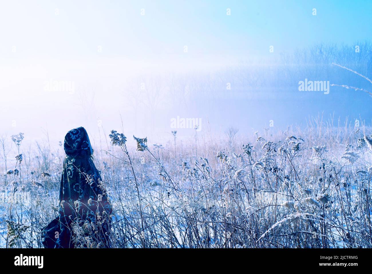 Shaman medieval woman in snowy marsh greeting the misty morning. Stock Photo