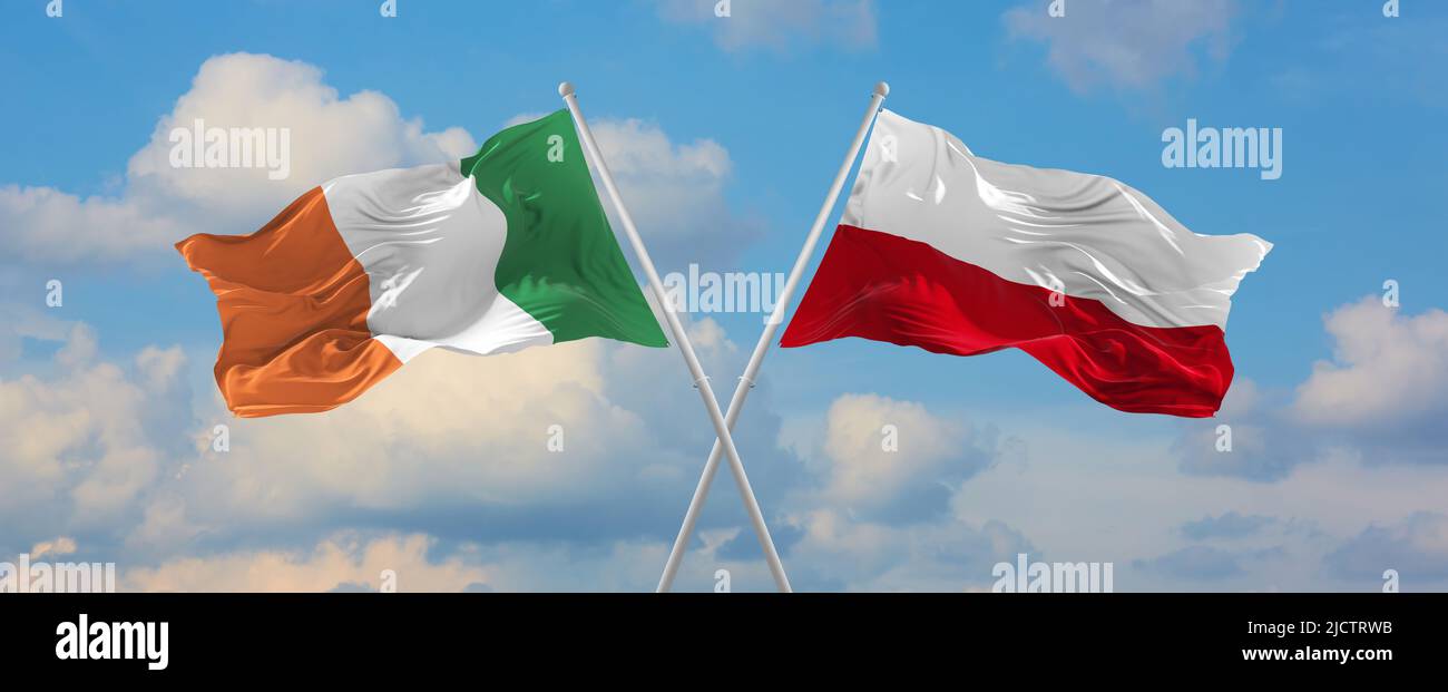 two crossed flags Ireland and Poland waving in wind at cloudy sky ...