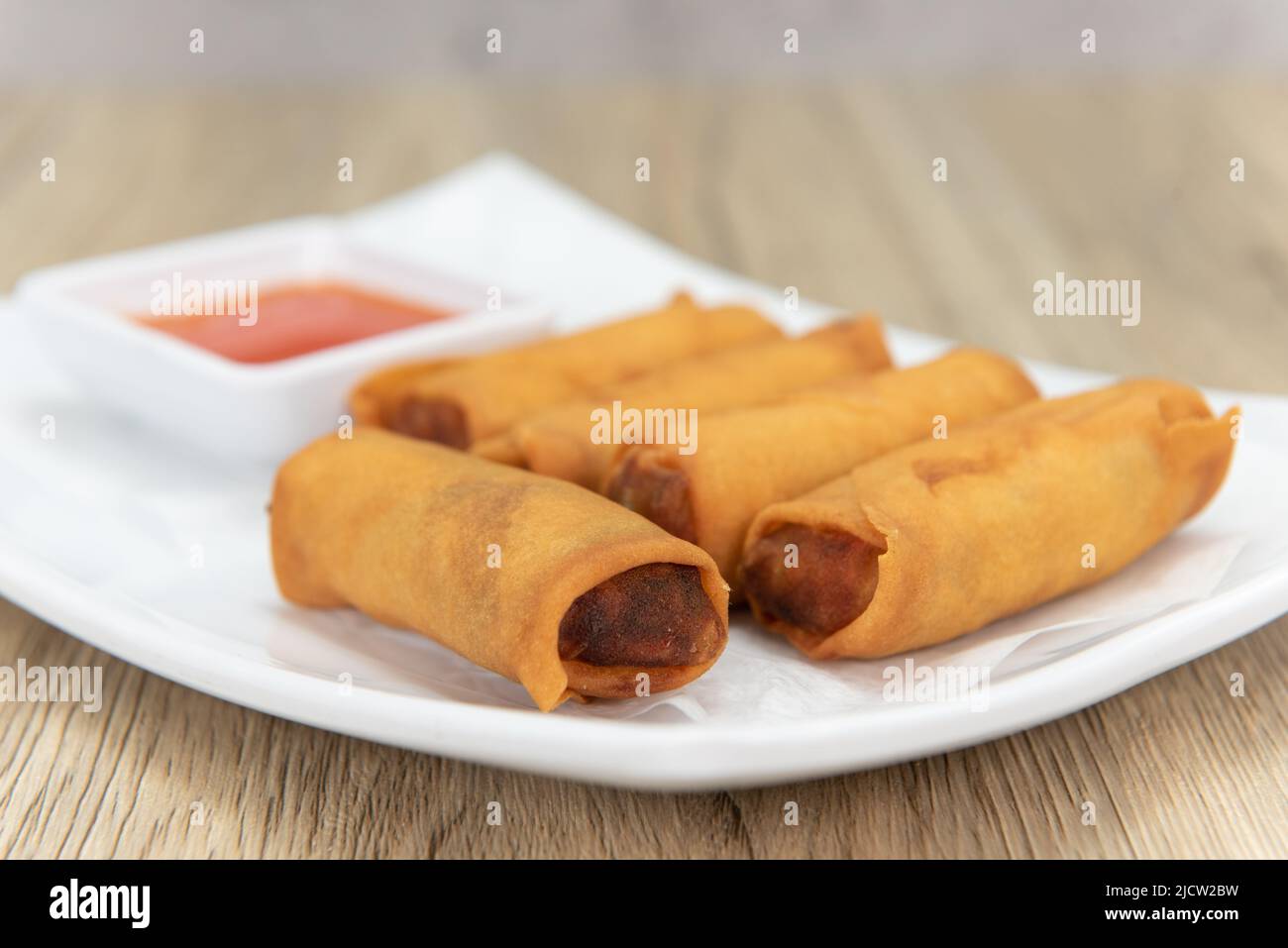 Tempting side order of crispy crunchy egg rolls with sweet and sour sauce to dip and ready to eat. Stock Photo