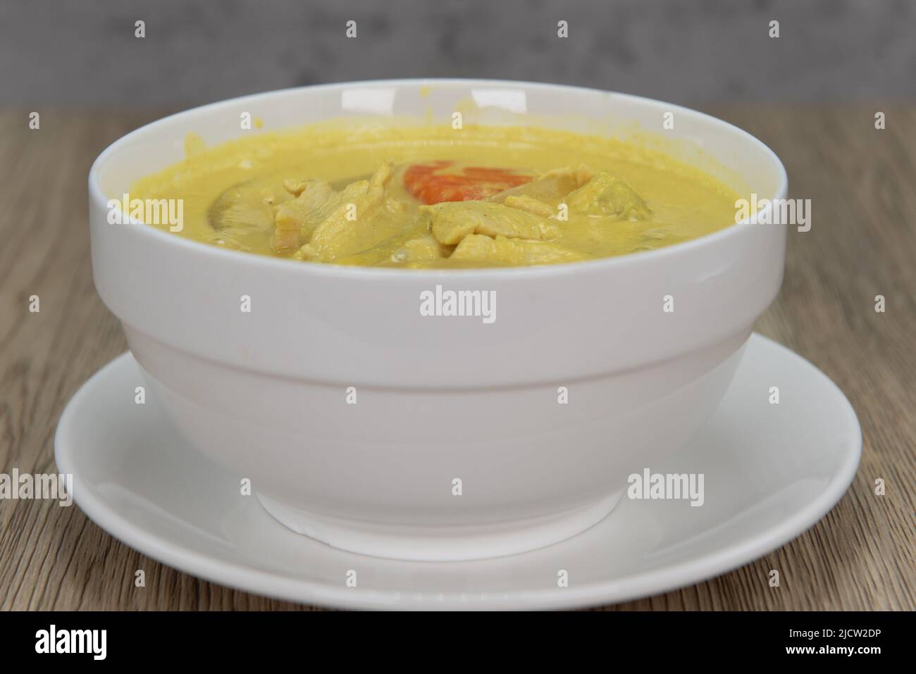 Spicy yellow curry with decorative garnishment served in a bowl and ready to eat. Stock Photo