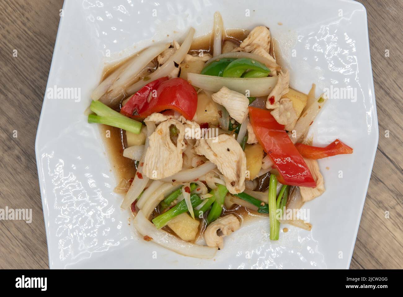 Overhead view of spicy plate of chicken with vegetable stir fry, topped with pineapple and ready to eat. Stock Photo