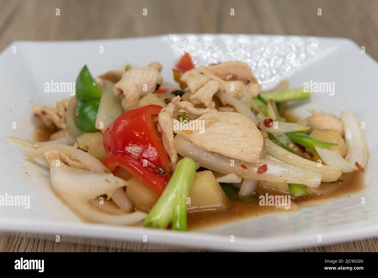 Spicy plate of chicken with vegetable stir fry, topped with pineapple and ready to eat. Stock Photo