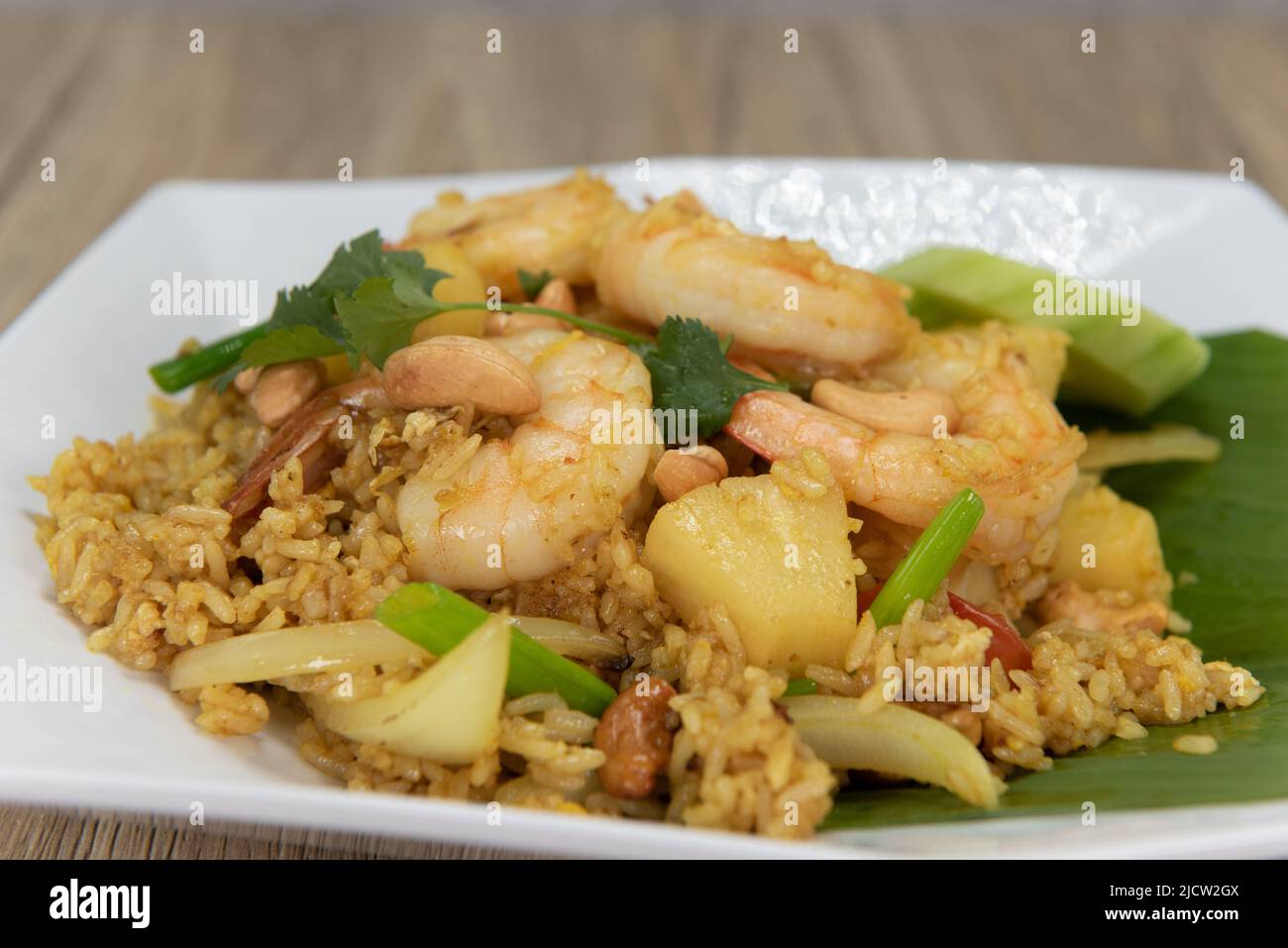 Pineapple fried rice plate topped with large shrimp, generous slices of cucumber and ready to eat. Stock Photo