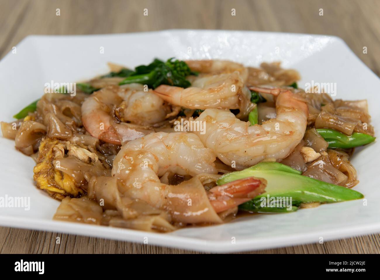 Appetizing plate of pad see-ew with large shrimp garnishing the top and ready to eat. Stock Photo