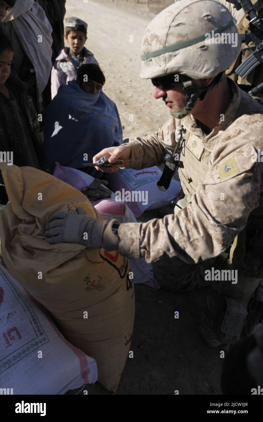 A U.S. Marine with Weapons Company, 1st Battalion, 8th Marine Regiment (1/8), Regimental Combat Team 6, cuts open a suspected bag of illegal fertilize Stock Photo