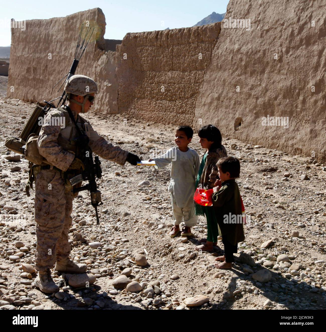 A U.S. Marine with Weapons Company, 1st Battalion, 8th Marine Regiment (1/8), Regimental Combat Team 6, hands out candy to Afghan children while patro Stock Photo