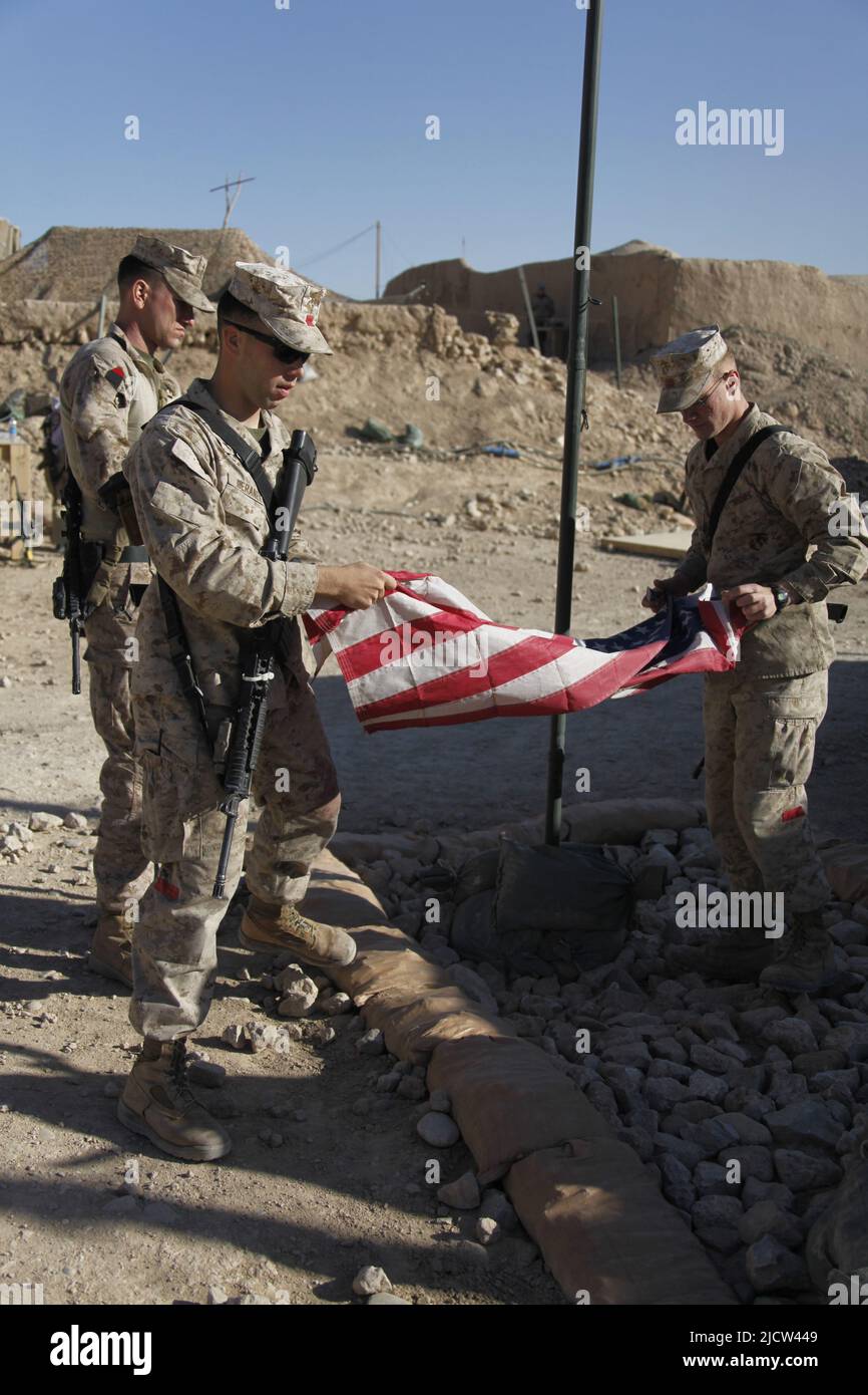 U.S. Marine Corps Sgt. James M. Mercure Jr. (left) with 1st Marine Expeditionary Force Forward, holds a folded American flag that is going to be raise Stock Photo
