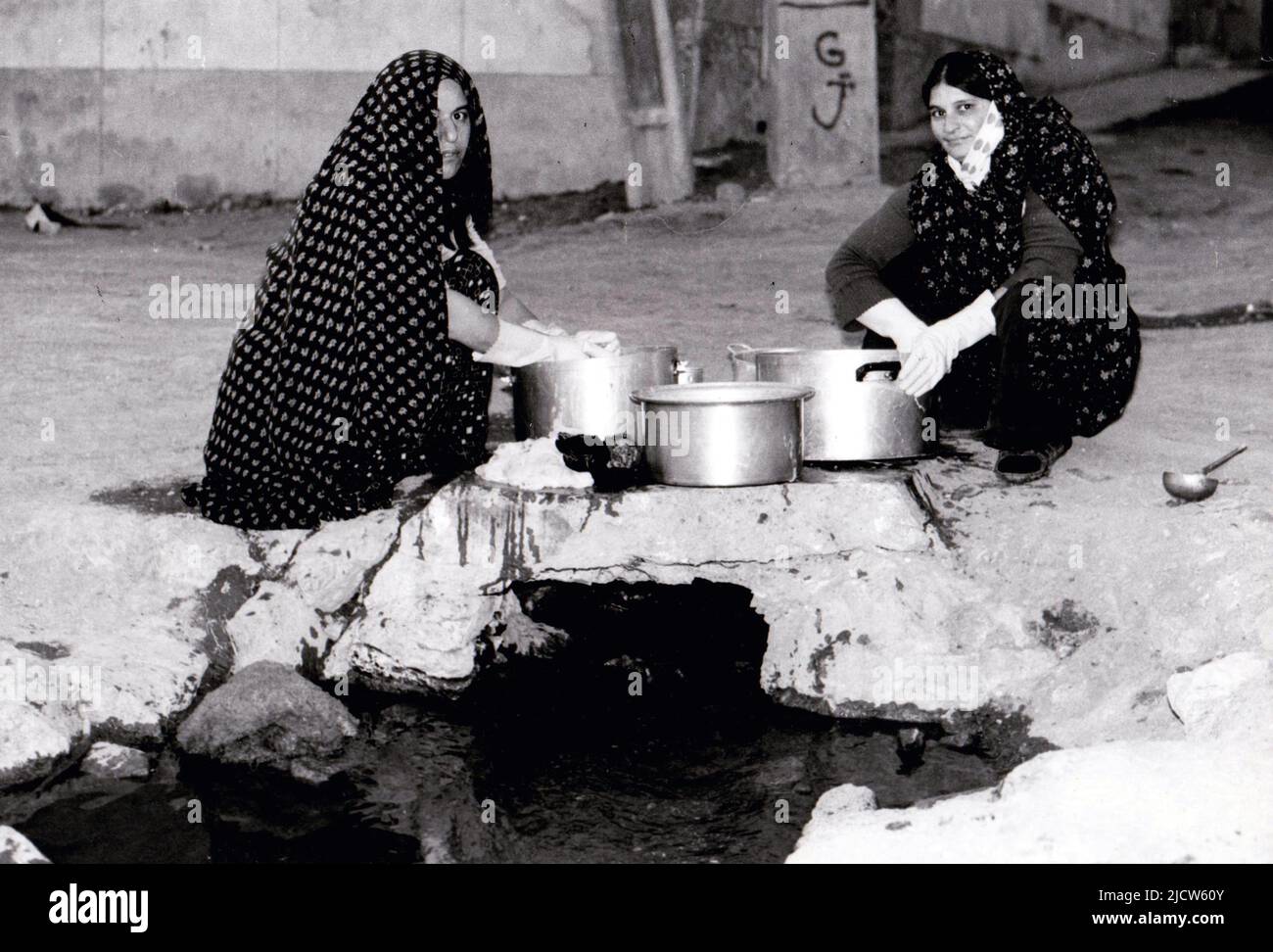 Women washing up in a gutter in downtown Tehran. They were known as jube women,1978. Stock Photo