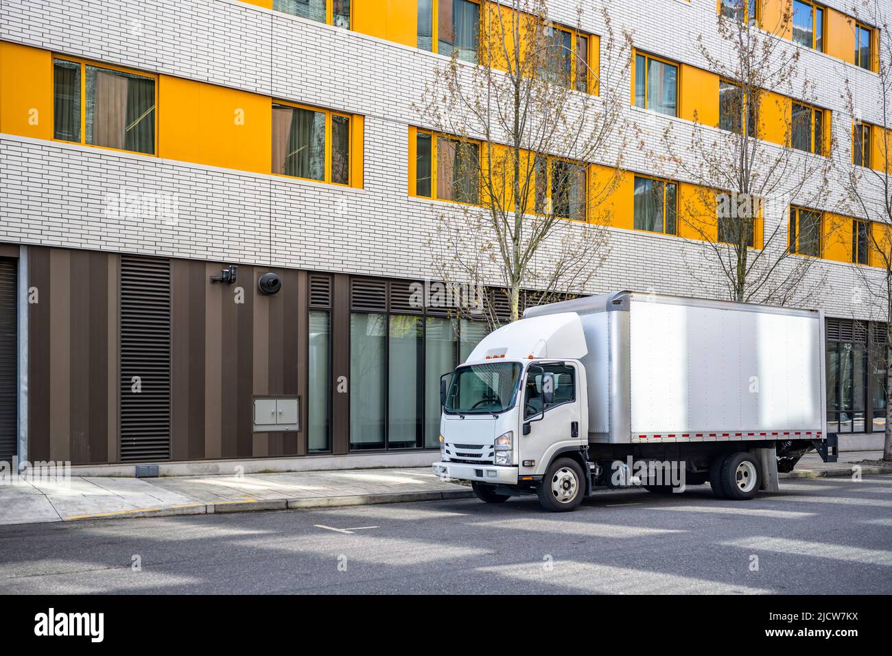 Small rig over cab white semi truck with long box trailer making local ...